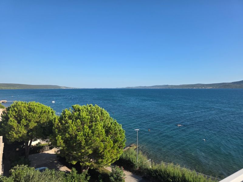 Sea view from a 4-room apartment in Sukošan, surrounded by green trees and a clear sky.