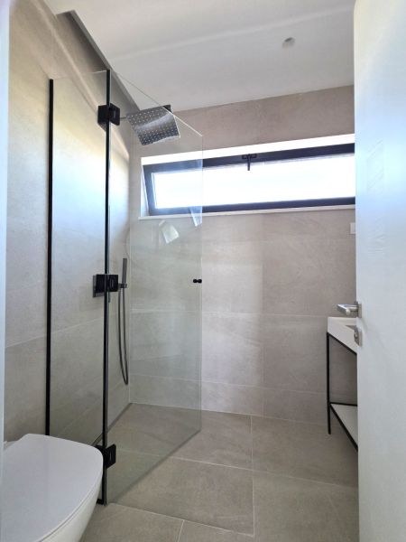 A bathroom with a glass shower and a sink in a 4-room apartment.