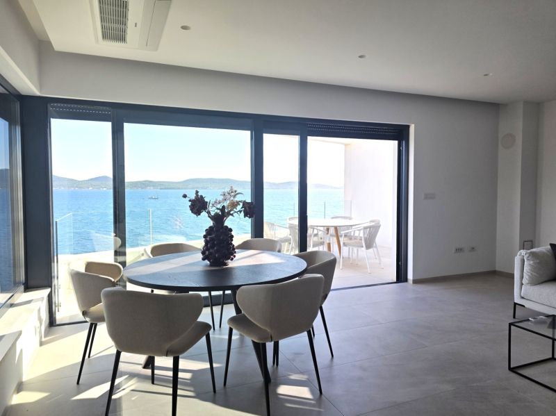 Living room with a table and chairs, large window with a sea view.