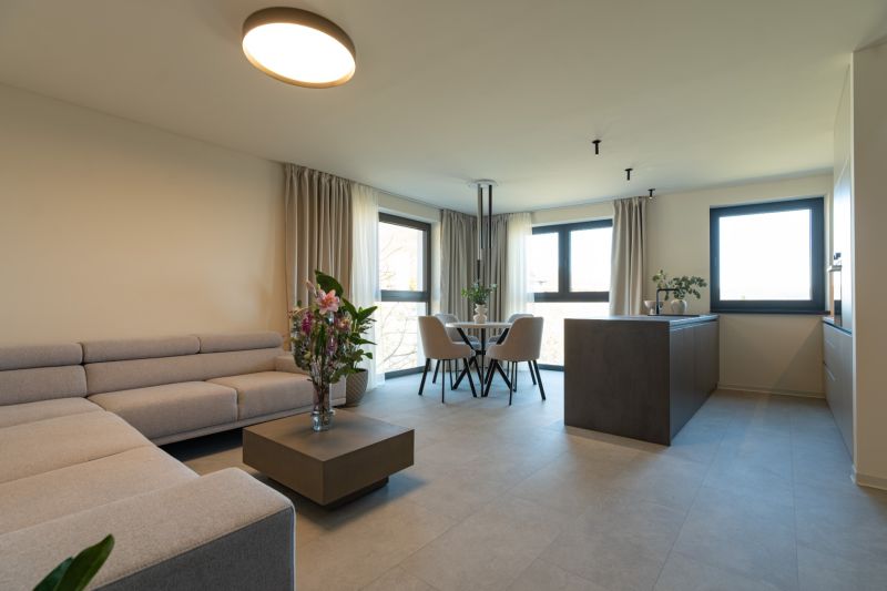 Living room with a sofa, flowers, dining table, and kitchen island in a 4-room apartment.