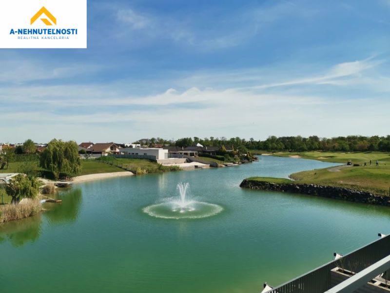 A view of the lake with a fountain and surrounding greenery on Golfová Street in Hrubá Borša.