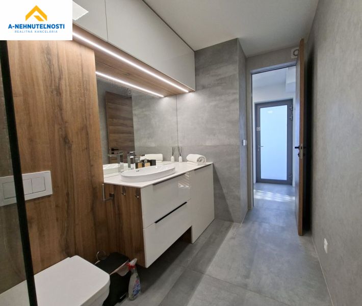 Bathroom in a 2-room apartment with a bathtub, wooden decor, and light tiles.