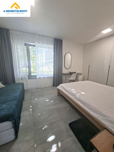 Bedroom in a two-room apartment with a large window, built-in wardrobes, and a desk.