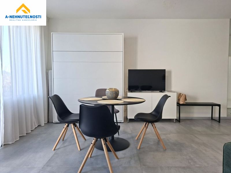 Dining area with a television and a table in a 2-room apartment with a wooden decor floor.