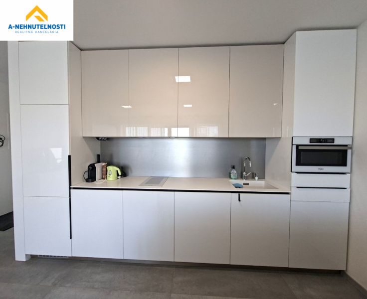 A kitchen in a 2-room apartment with a glossy white kitchen unit and built-in appliances.