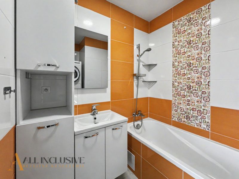 A bathroom in a 2-room apartment with a bathtub and orange tiles.