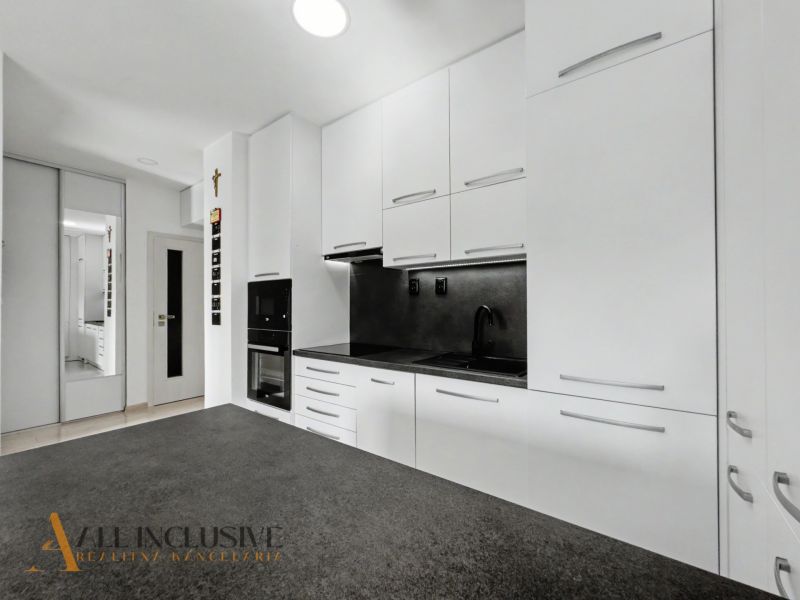 A kitchen in a 2-room apartment with a white kitchen unit and a mirrored wardrobe.