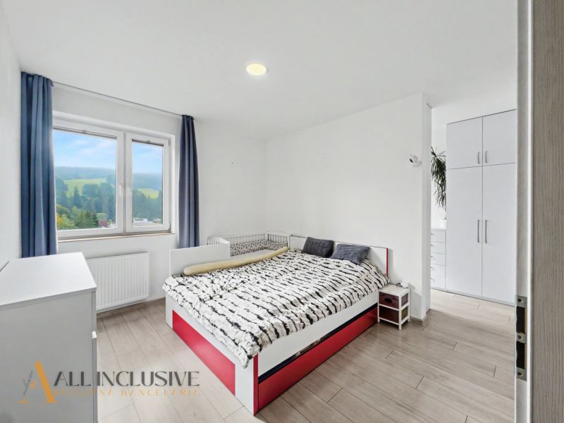 A bright bedroom with a bed, a wardrobe, and a wooden decor floor in a 2-room apartment.
