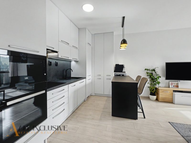 A kitchen in a 2-room apartment with white cabinets and a wooden decor floor.