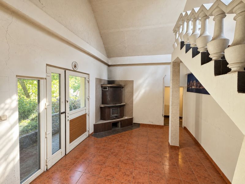 Interior with a tiled stove, staircase, and floor with a design in a residential plot.