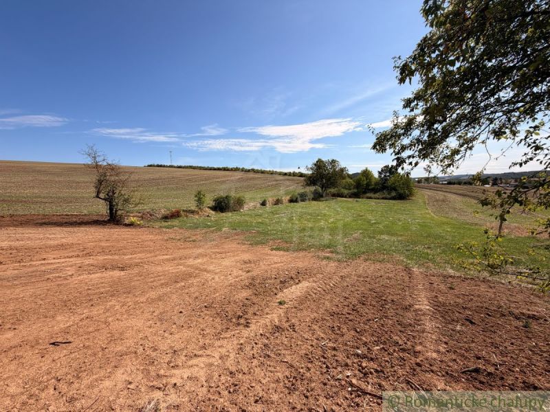A plot for living in a village surrounded by grass and fields. Treeless landscape on the horizon.