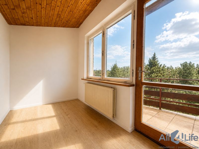 A room in a cottage with a wooden decor floor and a view of the forest.