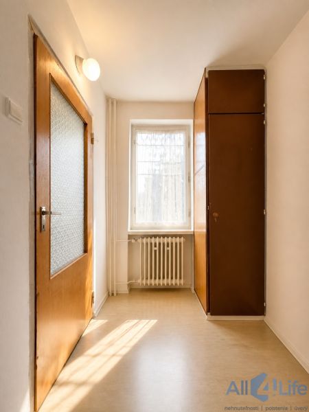 A bright hallway with doors, a window, and a built-in wardrobe in a cottage.
