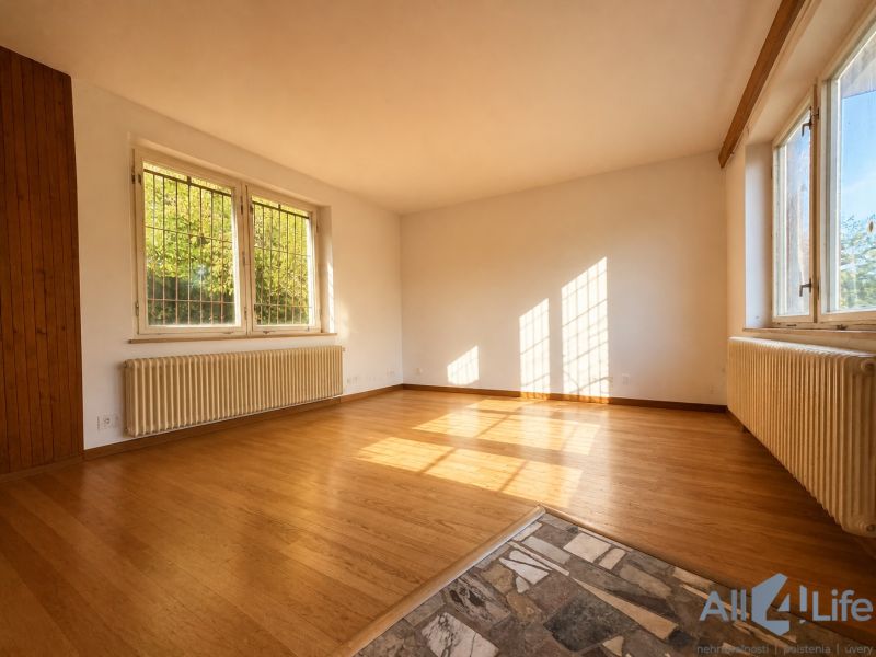 A bright room in a cottage with a wooden decor floor and large windows.