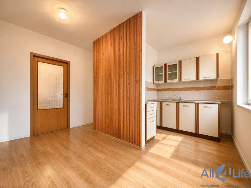 A kitchenette in a cottage with a wooden decor floor and a window.