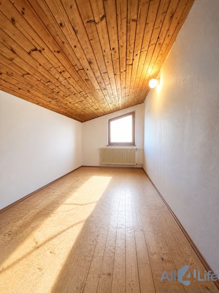 The interior of a cabin with a wooden decor floor and a wooden ceiling.