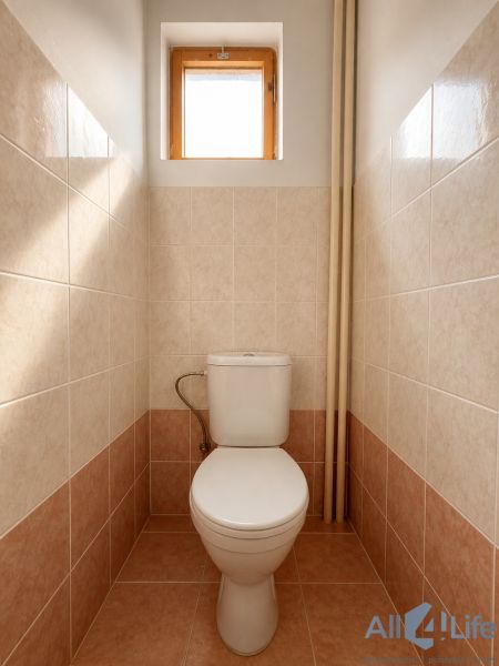 A toilet in a cabin with ceramic tiles and a small window.
