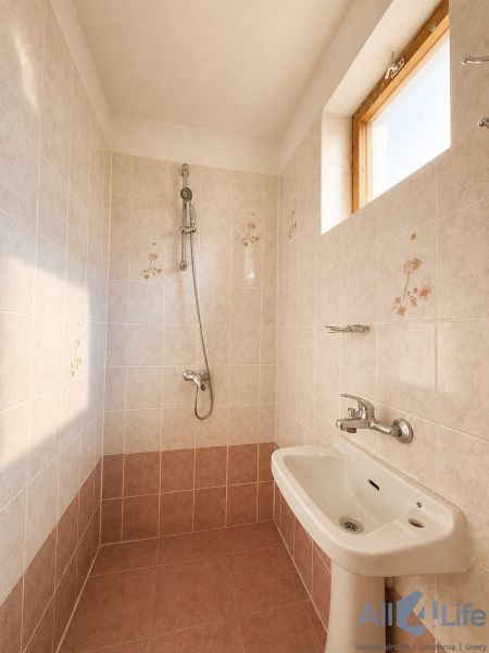 Bathroom in a cabin with ceramic tiles and a shower, floor with wooden decor.