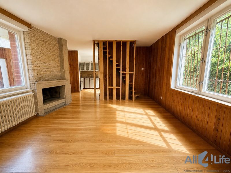 Interior of a cabin with wooden floor decor, a fireplace, and stairs leading to the upper floor.
