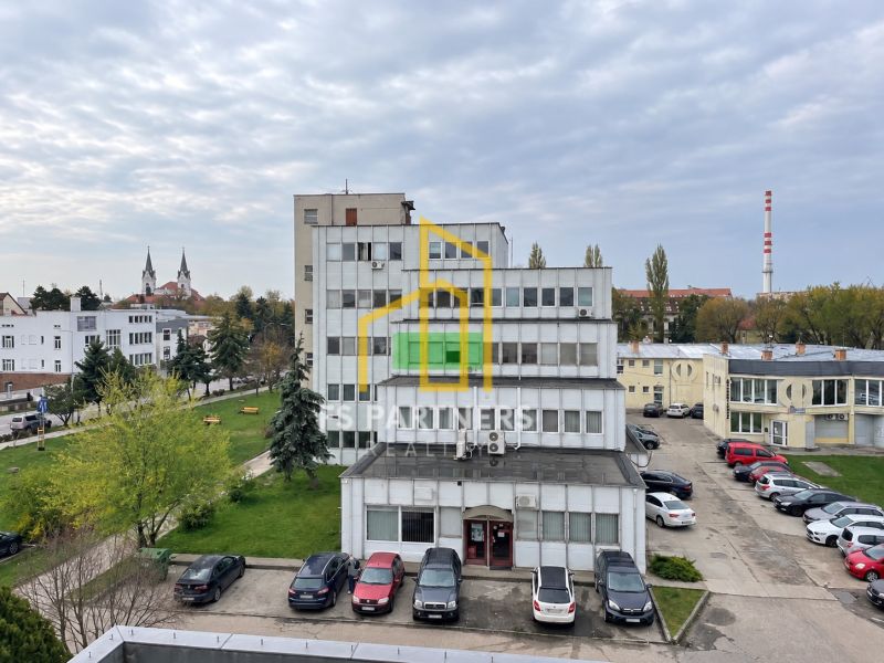 Building on Záhradnícka Street in Komárno, in front of it a parking lot and greenery.