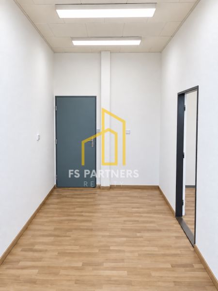 Room with closed doors in an office, floor with wooden decor, white walls.