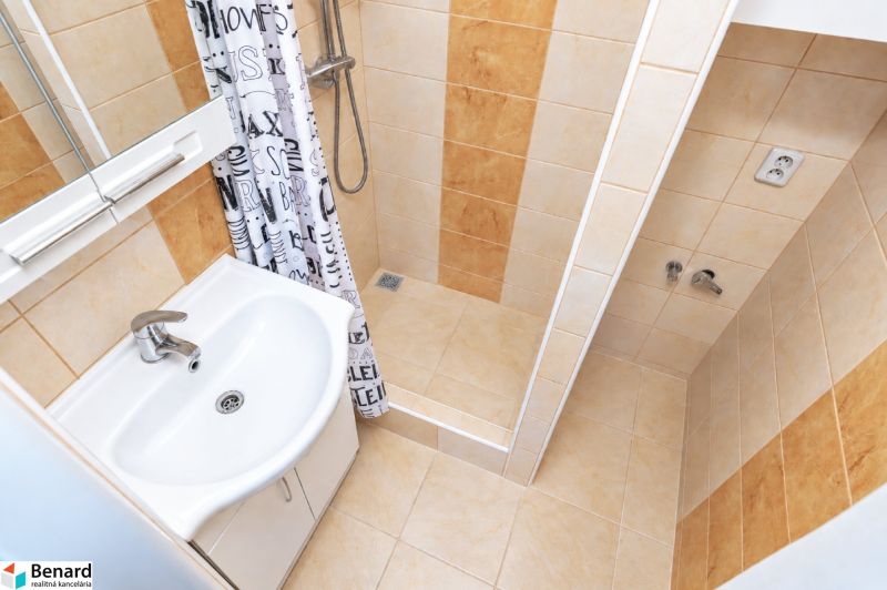 Bathroom in a 2-room apartment with a sink, shower corner, and tiles.