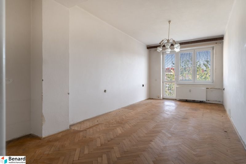 A spacious room with a wood-decor floor in a 2-room apartment.