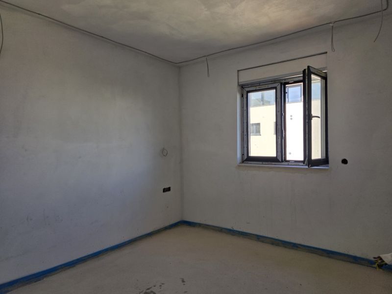 A room in a 3-room apartment with a concrete floor and an open window.