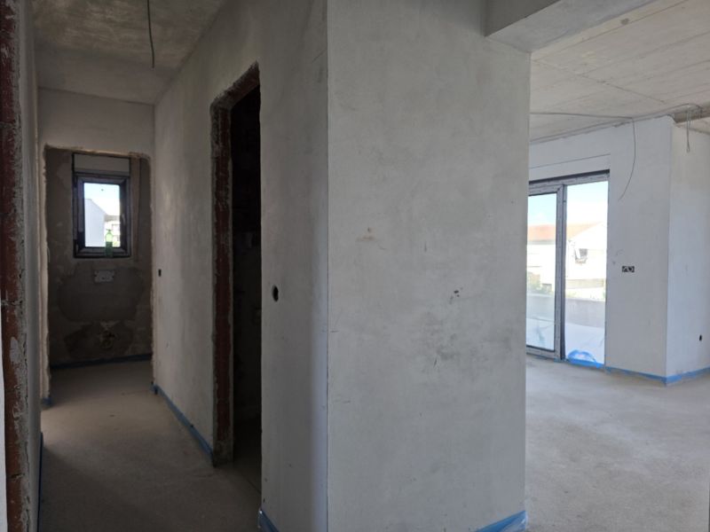 Unfinished 3-room apartment with concrete walls and large windows.
