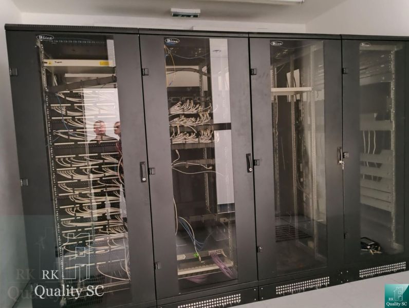 Server cabinets in offices with network cabling and the mirror reflection of people.
