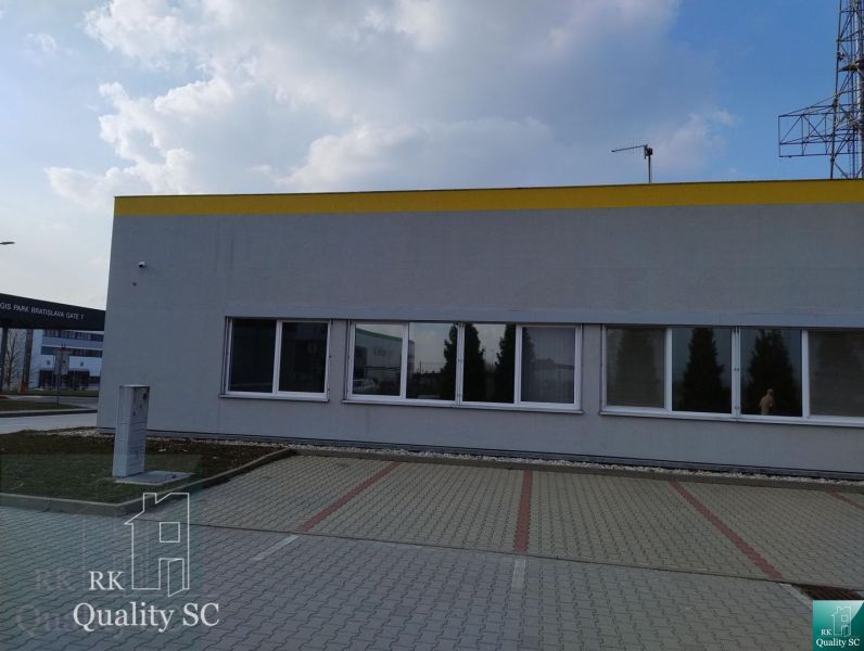 Offices in Senec with an outdoor parking lot, gray facade, and blue sky.