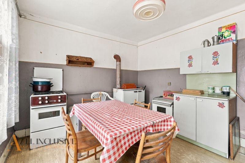 A kitchen in a family house with a kitchen unit, a stove, and a table with a checkered tablecloth.