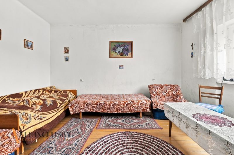 A room in a family house with beds, rugs, and a floor with a wooden decor.
