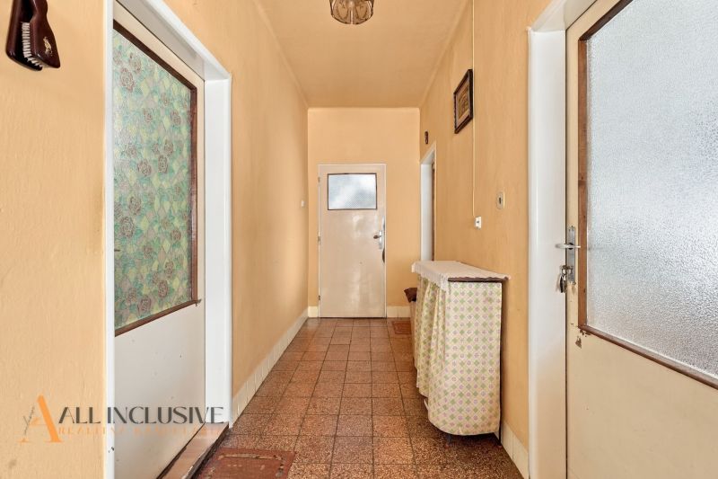A narrow hallway in a family house with a smooth floor and soft orange walls.