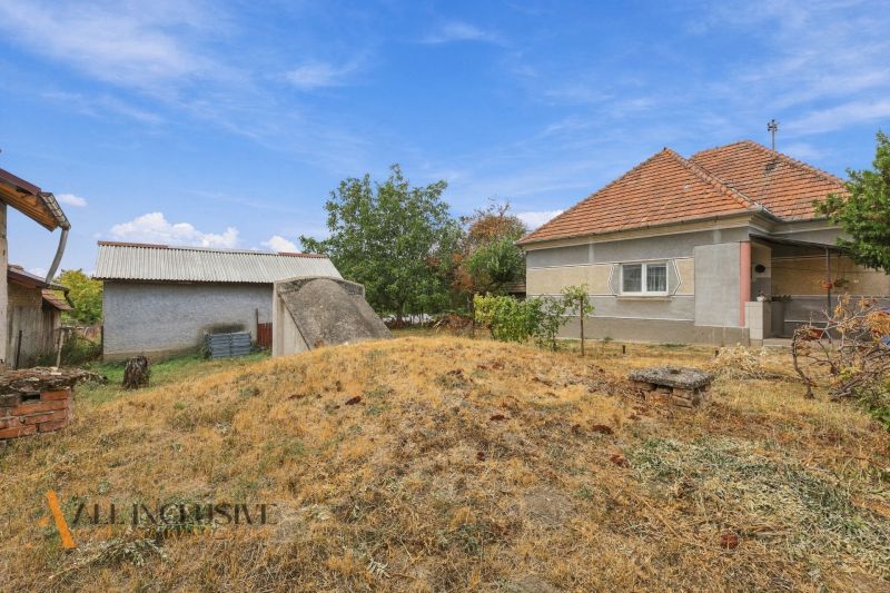 A family house in Bátorove Kosihy with a sloped roof and dry grass in the yard.
