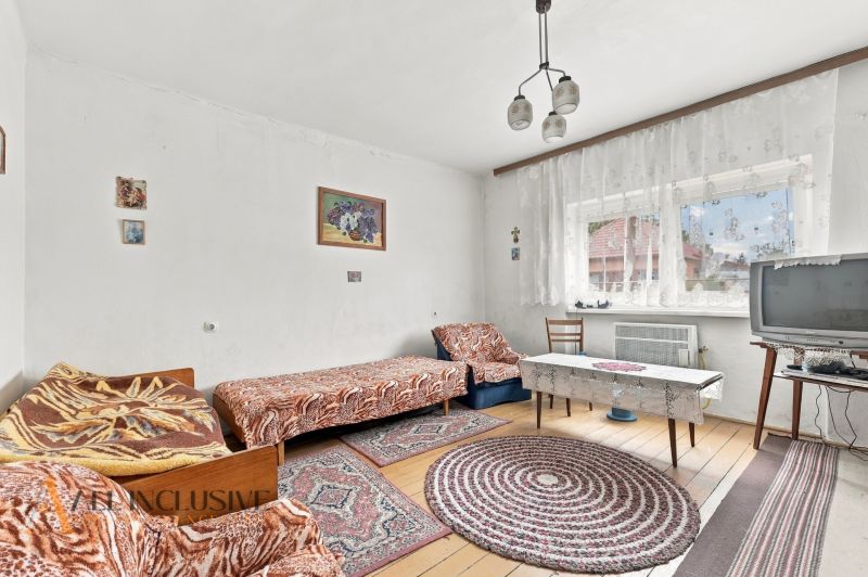 A room in a family house with beds, a television, and a floor with a wooden decor.
