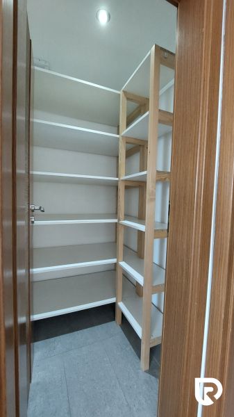 Storage space with shelves in a 2-room apartment, floor with wood decor.