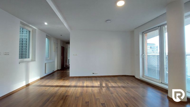 Living room in a two-room apartment with a wooden decor floor and large windows.