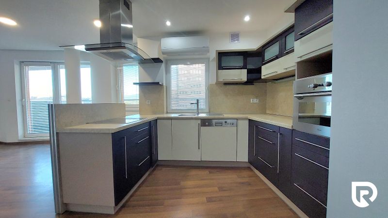 A kitchen in a 2-room apartment with a wood-patterned floor and built-in appliances.