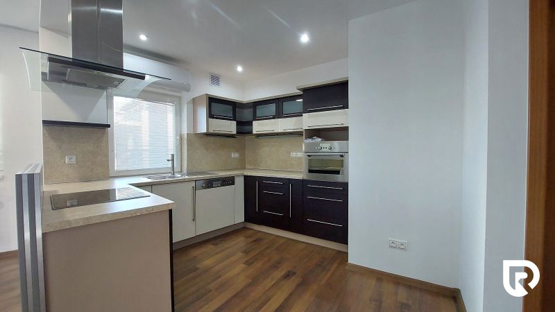 A kitchen in a 2-room apartment with dark furniture and a wooden decor floor.