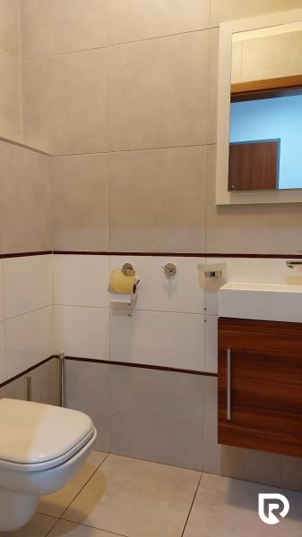 Bathroom with a mirror and toilet in a 2-room apartment, tiles and wooden paneling.