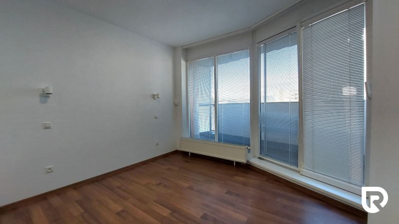A room with a wooden decor floor and large windows in a two-room apartment.