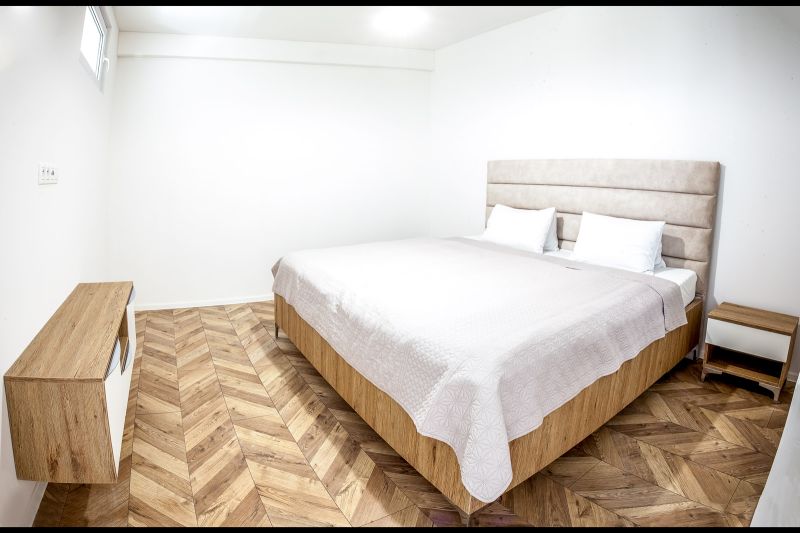Bedroom in a holiday apartment with a bed and wooden decor flooring.