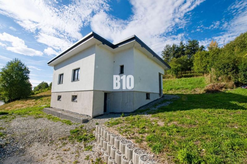 A family house in Skalité surrounded by greenery and a clear blue sky.
