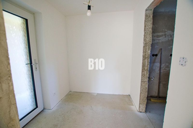 Room in a family house with a concrete floor and glass doors.