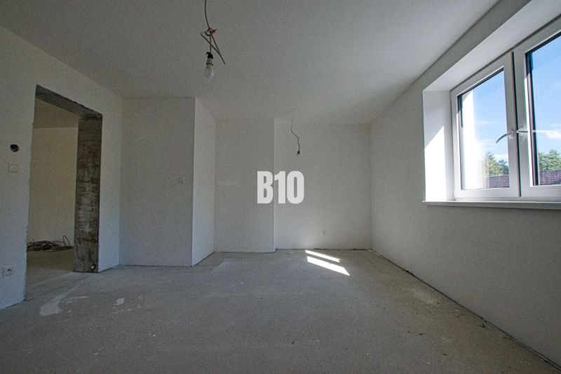 Interior of a family house with white walls, a large window, and a concrete floor.