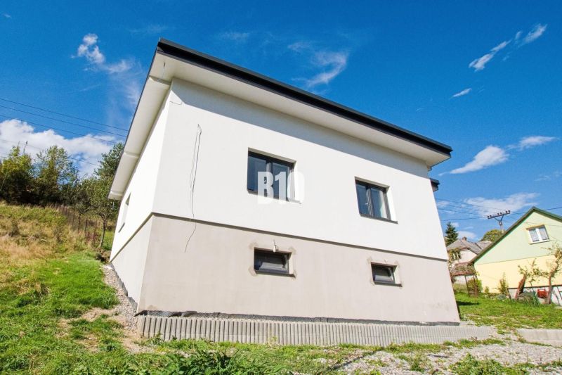 A yellow family house in Skalité surrounded by grass and a blue sky.