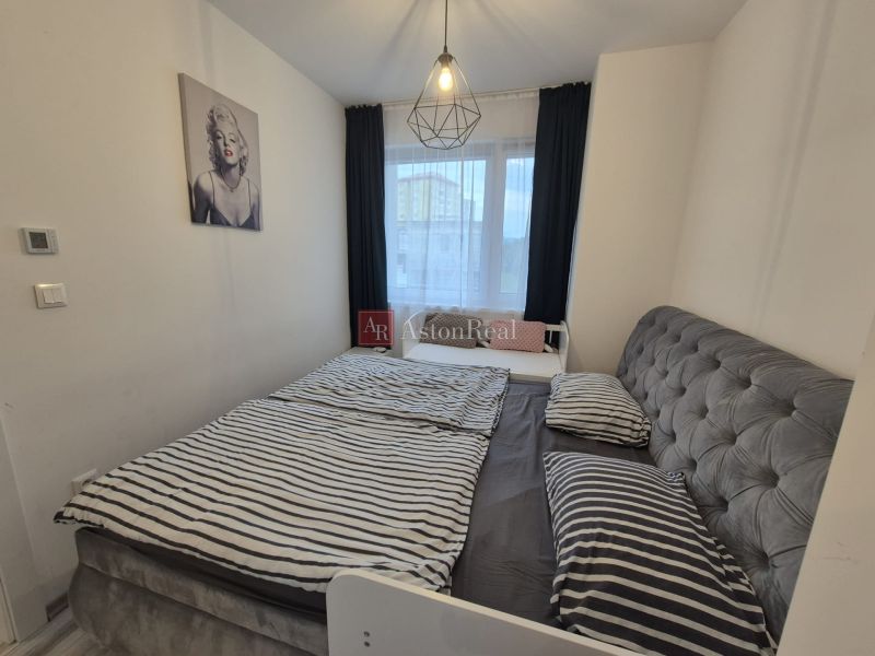 Bedroom in a 3-room apartment with a bed, a painting, and simple lighting.