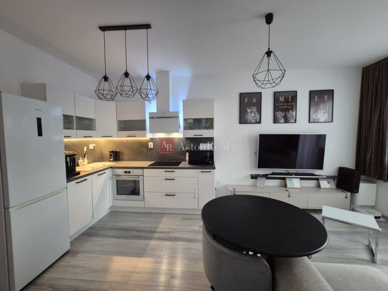 A kitchen in a 3-room apartment with a wooden decor floor and white cabinets.