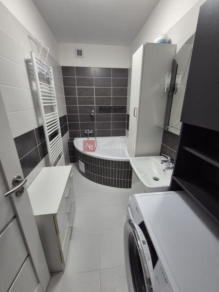 A bathroom with a bathtub, sink, washing machine, and cabinet in a 3-room apartment.